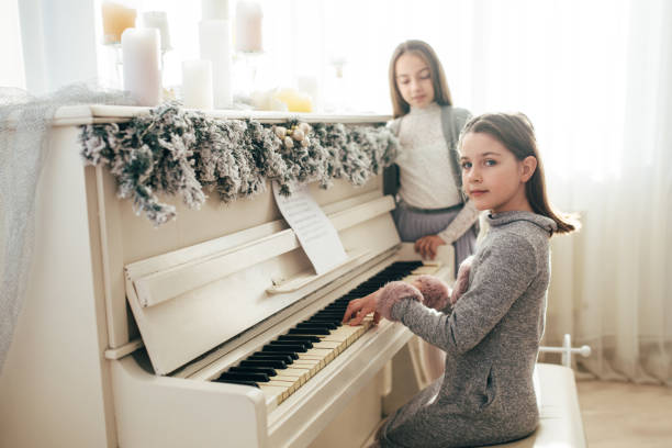 istock Two pretty sisters sitting at white fortnpiano 890173942