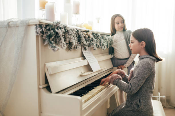 istock Two pretty sisters sitting at white fortnpiano 890174004