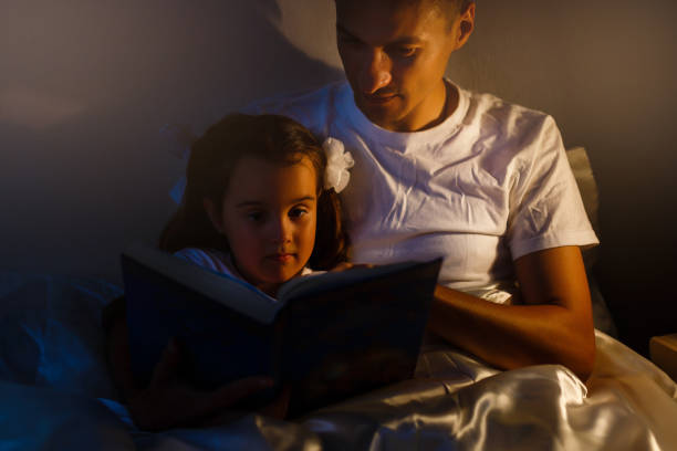 istock Caring father is reading a book to his little daughter before bedtime 890214672