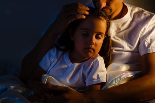 Little daughter fell asleep at the father while reading the book