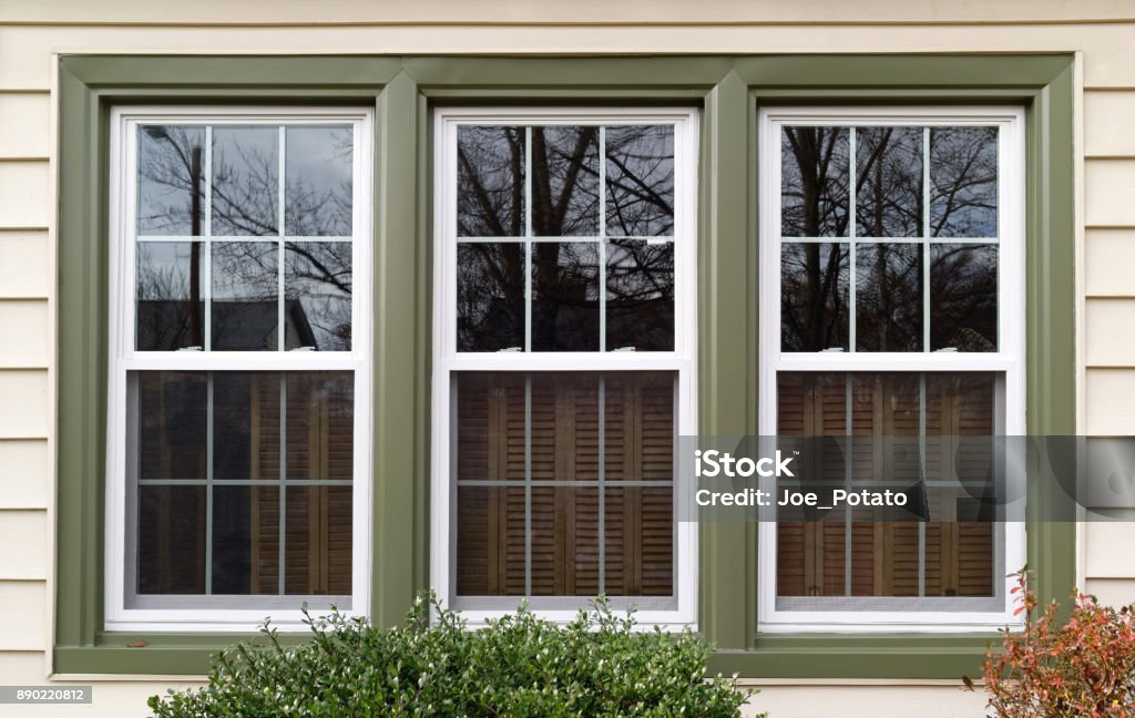 Replacement Windows Three new replacement windows with green trim on front of house. Horizontal. Window Stock Photo