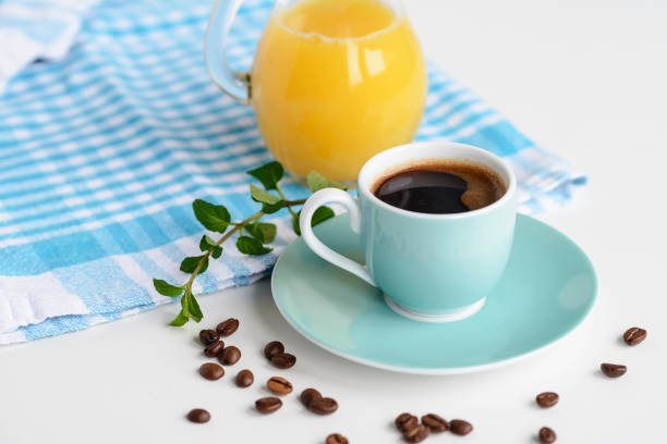 istock Strong black coffee in a light blue cup on a white table with orange juice. 890234050