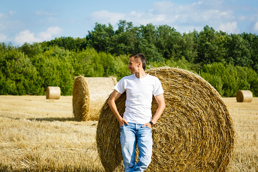 Happy smiling caucasian thirty years old farmer standing proud in front of his wheat fields