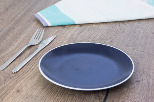 istock Empty blue plate, cloth napkin and cutlery set on wooden table. 890260946