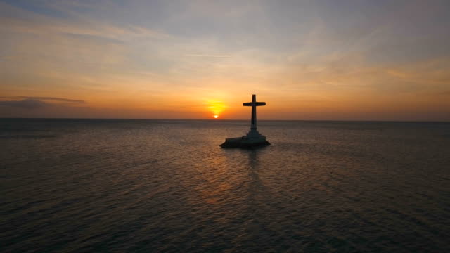 Catholic cross in the sea at sunset
