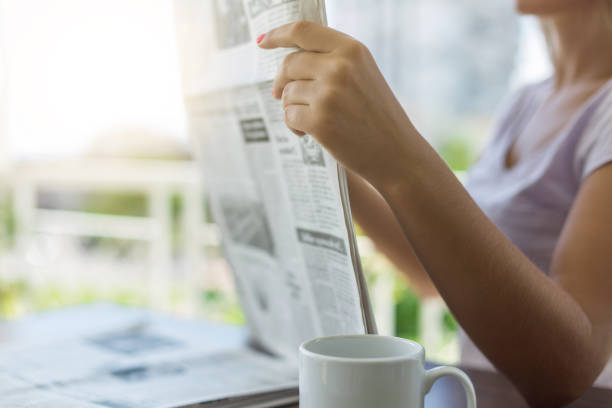 istock Young woman reading newspaper on balcony 890270376