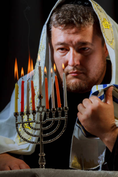 ハヌカのため供さ本枝の燭台のテーブルで男の手照明キャンドル - menorah hanukkah candle human hand ストックフォトと画像