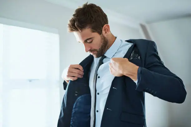 Shot of a handsome young man dressing himself at home