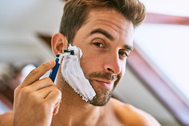The beard has to go Shot of a handsome young man shaving at home shaving stock pictures, royalty-free photos & images