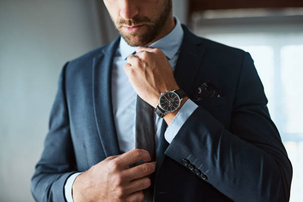 The perfect outfit means a perfect day Shot of an unrecognizable man dressing himself at home tying photos stock pictures, royalty-free photos & images