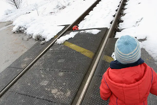 Child playing with his ball on tracks.
