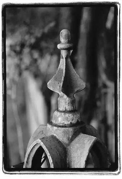 Fence top spire on an old cemetery fence. Original black & white on film, visible grain. printed with filed out neg carrier frame.