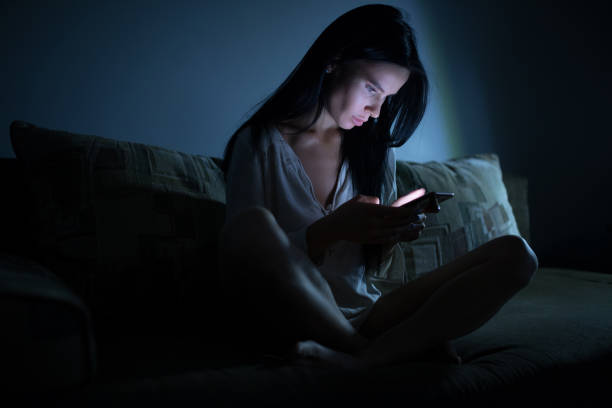 istock Tired woman using blue smartphone screen at night dark room 890305564