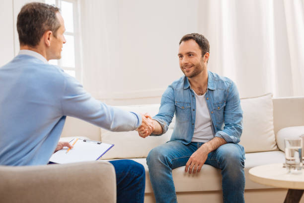 happy glad man shaking hands with psychologist - doctor patient greeting talking imagens e fotografias de stock