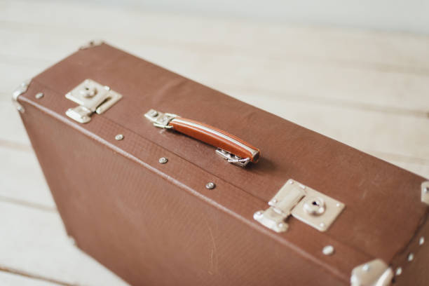istock Old brown suitcase on the white boardwalk floor 890319636