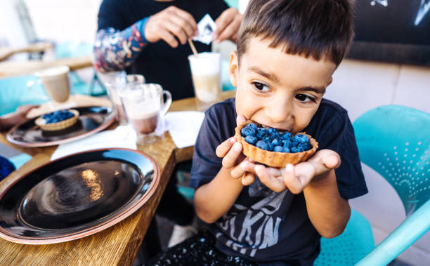 small boy eating dessert with blueberries stock photo