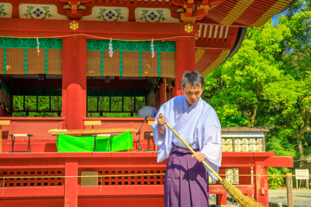 Kamakura, Japan - April 23, 2017: close-up of Shinto priest who cleans inside Tsurugaoka Hachiman Shinto shrine in the city of Kamakura, Kanagawa Prefecture.