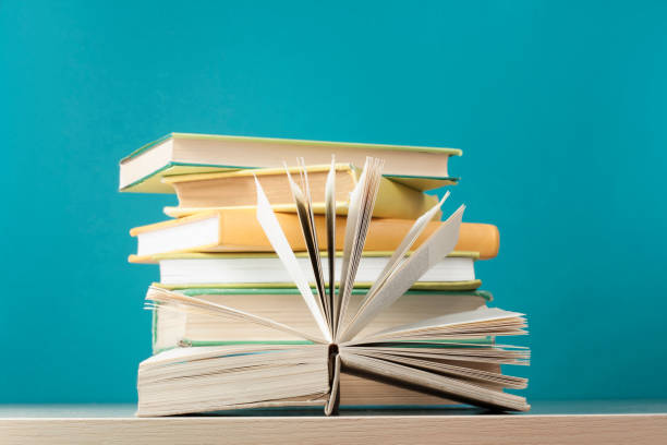 istock Composition with open book, hardback books on wooden table and blue background. Back to school. Copy space for text. Education background. 890358148