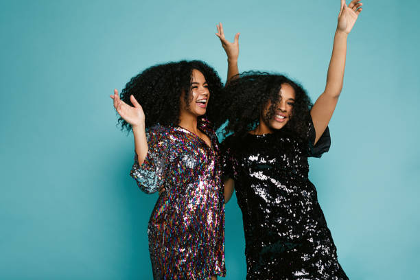 istock Two women dancing in studio against blue background with raised hands 890358314