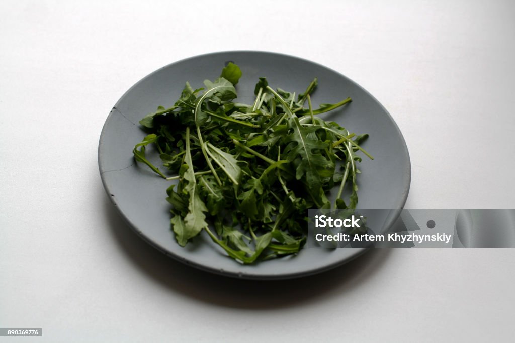 Bunch of arugula on plate Bunch of arugula salad isolated on gray concrete plate Arugula Stock Photo