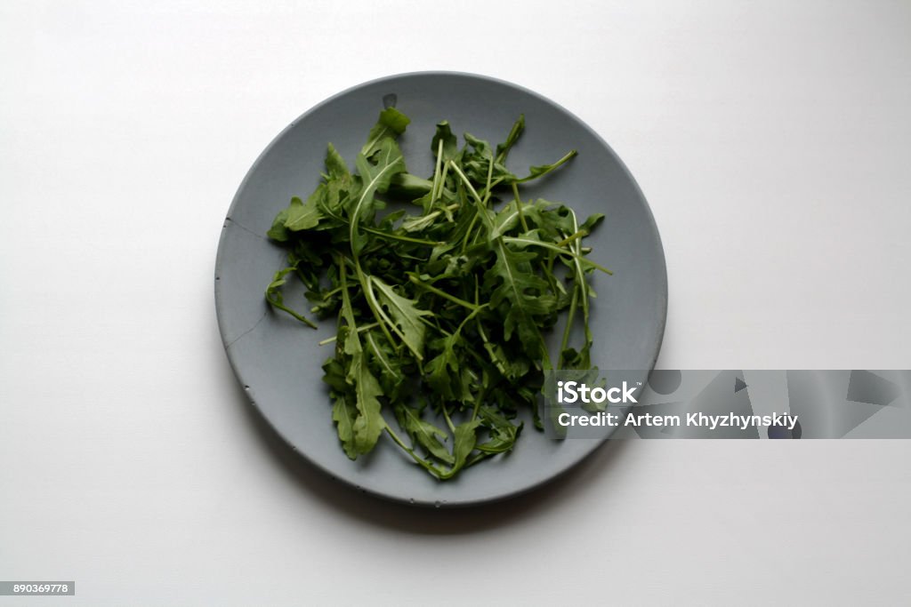 Bundle of arugula on plate from above Bundle of arugula salad isolated on gray concrete plate from a high angle view Arugula Stock Photo