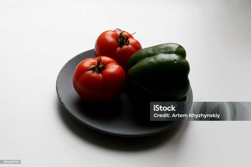 Tomatoes and poblano pepper on plate Two tomatoes and green poblano pepper isolated on gray concrete plate Backgrounds Stock Photo