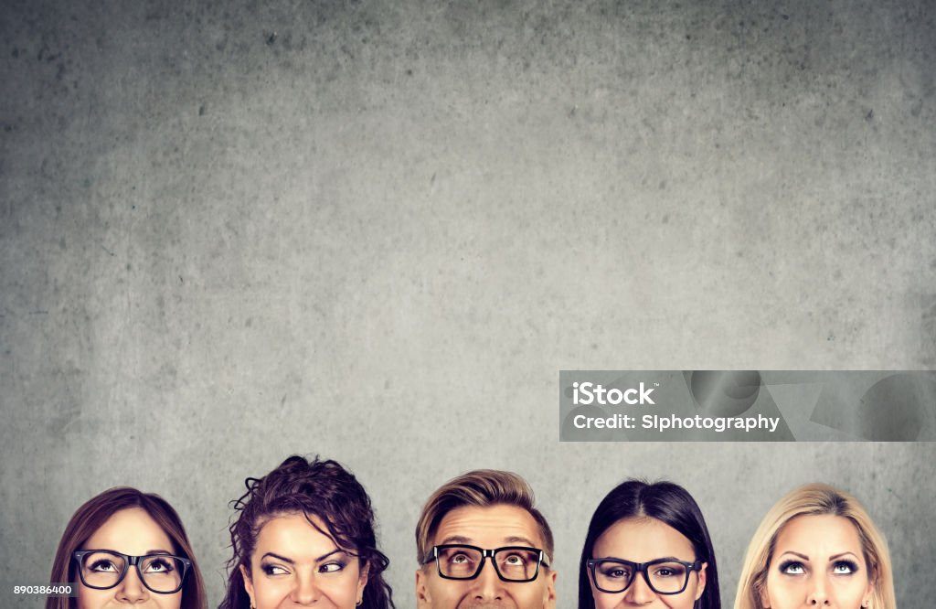Closeup of young people heads standing near a gray concrete wall. A diverse business team and  brainstorming concept Closeup of young people heads standing near a gray concrete wall. A diverse business team and brainstorming concept Contemplation Stock Photo
