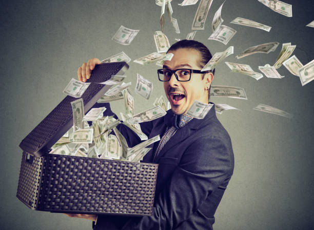 istock Excited successful man opening a box with money flying out away 890386434