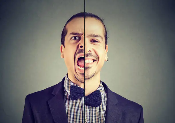 Photo of Bipolar disorder concept. Young business man with double face expression isolated on gray background