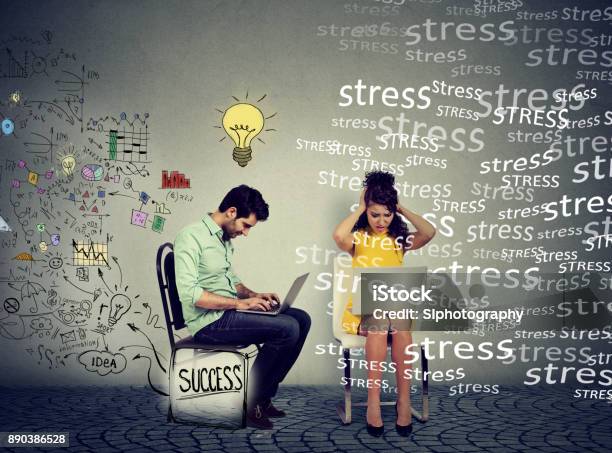 Successful Man With Clear Strategy Working On Laptop Computer Next To A Stressed Young Woman Stock Photo - Download Image Now