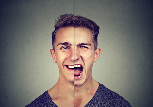Bipolar disorder concept. Young man with double face expression isolated on gray background
