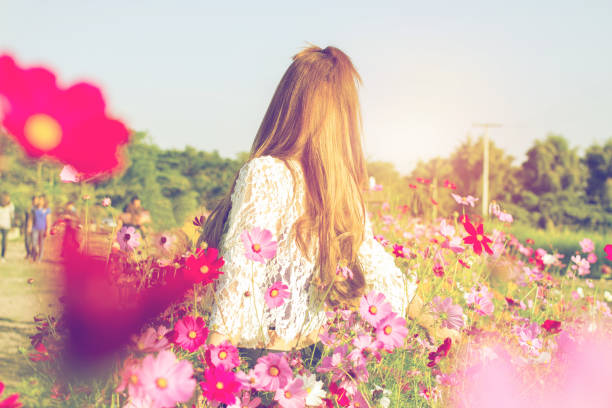 istock Female standing freely in the beautiful flower fields have sunset light. 890392804