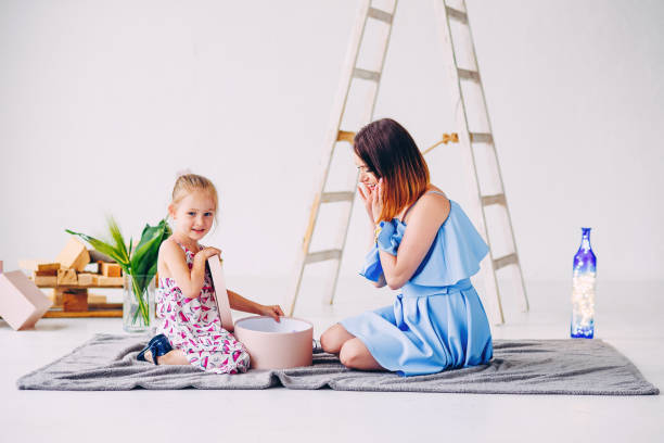 istock Happy smiling girl with her mom unpacks a gift. 890395410