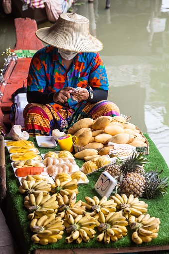 PATTAYA CITY, THAILAND – FEB, 3, 2017: Merchant vendor in Pattaya City floating open air market in the southeast asian country of Thailand selling produce from a boat.