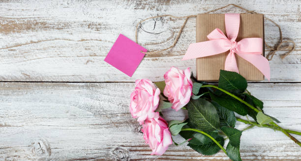 istock Pink roses and gift on rustic white wood 890408022