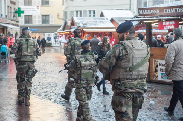 group of military patrolling with machines gun in christmas market Mulhouse - France - 9 December 2017  - group of military patrolling with machines gun in christmas market mulhouse photos stock pictures, royalty-free photos & images