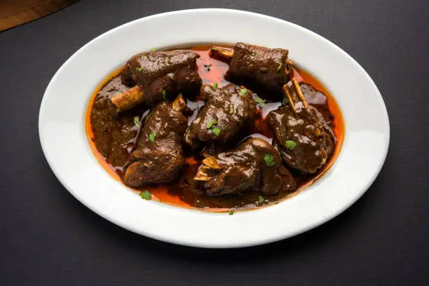 lamb shank or mutton or gosht paya or khoor curry served with indian bread or roti or naan