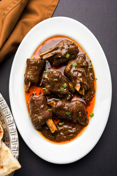 lamb shank or mutton or gosht paya or khoor curry served with indian bread or roti or naan - paya imagens e fotografias de stock