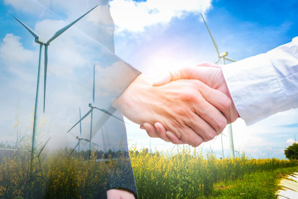 istock Double exposure of handshake with wind turbine. Ecology concept 890498332