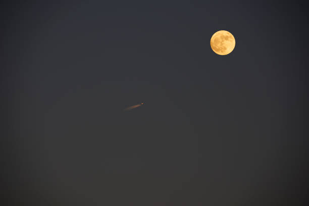 Vapor trails from jet airplane with full moon Vapor trails from jet airplane and red full moon on dusk sky with copy space. contrail moon on a night sky stock pictures, royalty-free photos & images