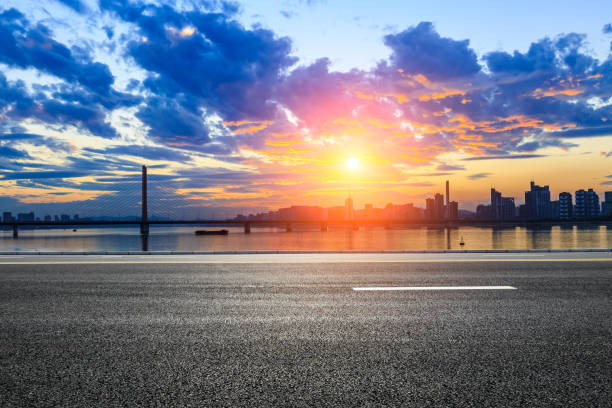 istock Empty asphalt road and city skyline at sunset 890545828