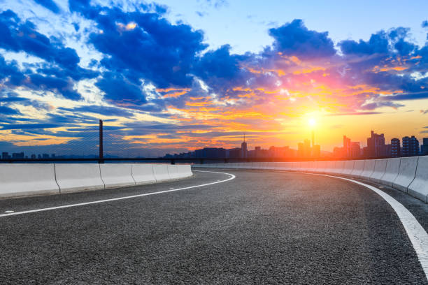 istock Empty asphalt road and city skyline at sunset 890545906