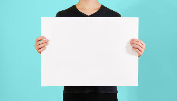 istock Man showing blank white big A2 paper. Leaflet presentation. Pamphlet hold hands. Man show clear offset paper. Sheet template. Booklet design sheet display read first person. 890554670