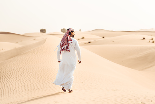 arabic man walking alone in the desert