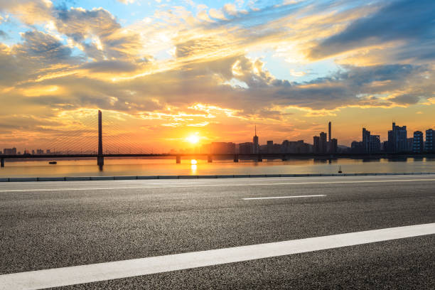 istock Empty asphalt road and city skyline at sunset 890575764