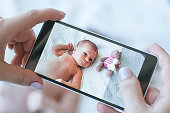 mother take a smartphone photo of her newborn baby