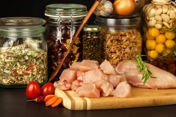 Raw chicken breast on the kitchen board. Diet food. Sale of meat. Spices for preparing meat on grill