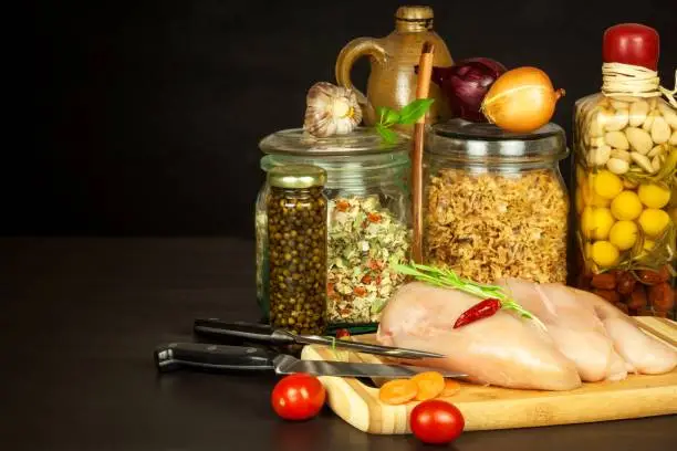 Raw chicken breast on the kitchen board. Diet food. Sale of meat. Spices for preparing meat on grill