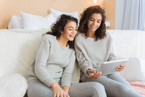 istock Positive minded girls beaming while looking at screen of touchpad 890597988