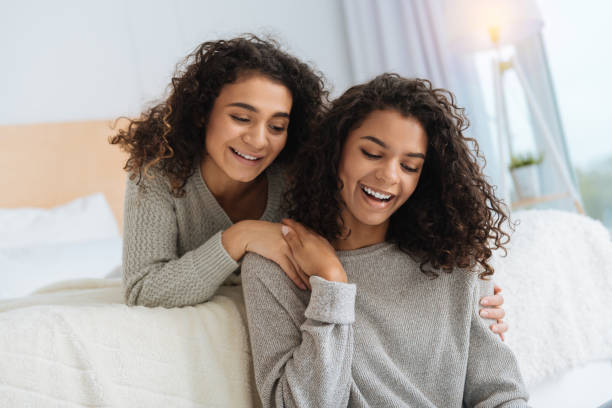 istock Adorable girls smiling while lying on bed and chatting 890598676